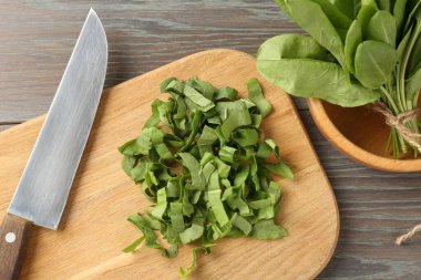 Taze at yaprakları ve bıçakla ahşap masada, düz yatıyordu.