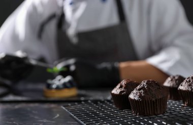 Şekerci, karanlık masada nane şekerli tart hazırlıyor, çikolatalı keklere odaklanıyor.