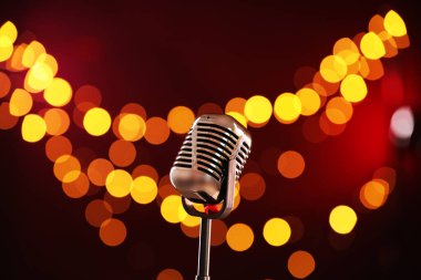 Koyu kırmızı arka planda bulanık ışıkları olan klasik mikrofon. Müzik ekipmanları