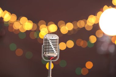 Karanlık arka planda bulanık ışıkları olan klasik mikrofon, mesaj için yer. Müzik ekipmanları