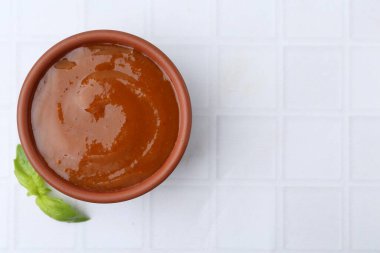 Lezzetli köri sosu ve fesleğen yaprakları beyaz fayanslı masa, üst manzara. Metin için boşluk