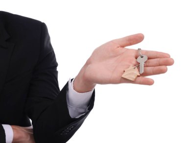 Beyaz arka planda ev anahtarı olan emlakçı, yakın plan.