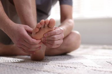 Acı çeken bir adam ayak altında, evde yerde, yakın plan.