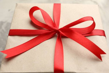 Kraft kağıdına sarılı hediye, gri desenli arka plan, yakın plan.