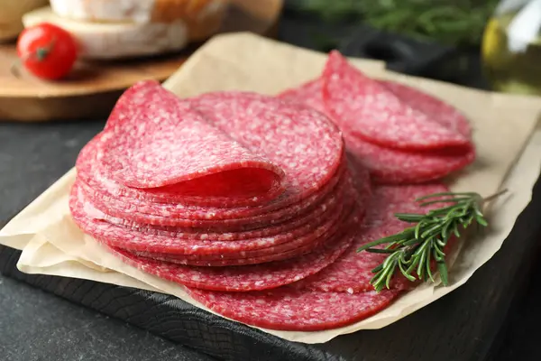 Lezzetli füme sosis ve biberiye dilimleri siyah masada, yakın plan.