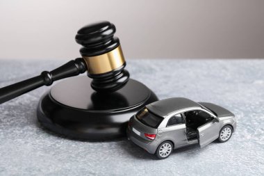 Motorlu taşıt kazası yasası. Gri arkaplanda Gavel ve araba modeli