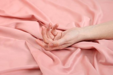 Yatakta pembe ipek çarşaflara dokunan kadın, yakın plan.