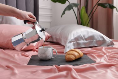 Yatağın üzerine güzel ipek çarşaflarla aromatik kahve koyan kadın, yakın plan.