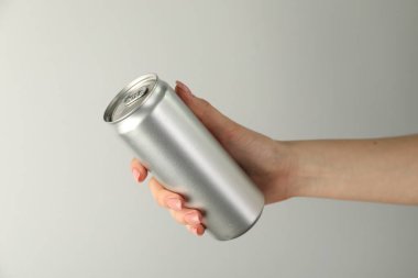 Açık gri arka planda teneke kutusu olan kadın, yakın plan.