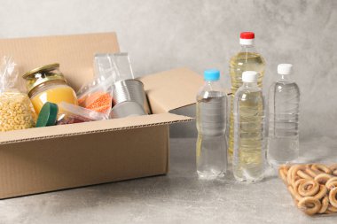 Şişeler dolusu su ve gri desenli masadaki farklı gıda ürünleri.