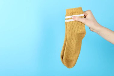 Açık mavi arka planda bir çift çorap giyen kadın, yakın plan. Metin için boşluk