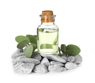 Bir şişe temel yağ, okaliptüs yaprakları ve beyaz üzerine izole edilmiş taşlar.