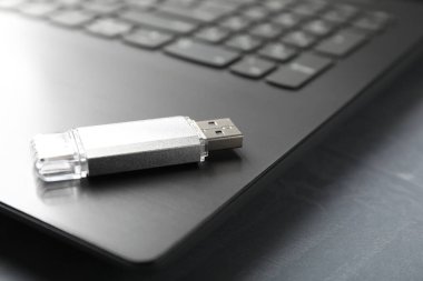 Gri desenli masadaki Usb flash diski ve laptop, yakın plan.