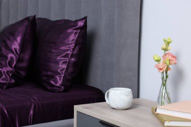 Lüks ipek çarşaflar yatağın üzerinde ve komodinin üzerinde.