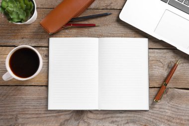 Boş defterleri, kahveyi, çiçekleri, dizüstü bilgisayarları ve kalemleri ahşap masaya aç, düz uzan.