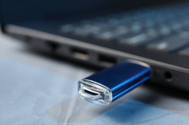 Gri masadaki dizüstü bilgisayara bağlı flaş bellek, yakın plan.