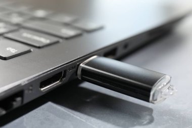 Gri desenli masadaki dizüstü bilgisayara bağlı flaş bellek, yakın plan.