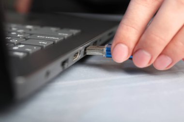 Gri masadaki flash belleğe bir kadın yerleştiriyor.