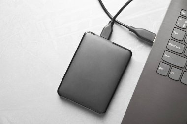 Gri desenli masadaki dizüstü bilgisayara bağlı harici sabit disk, üst görünüm