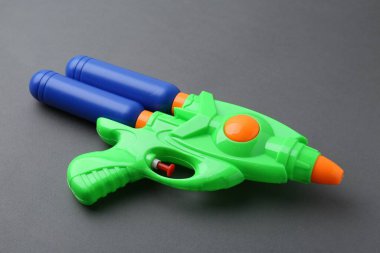 Gri arkaplanda parlak plastik su tabancası, yakın plan.