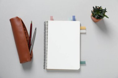 Açık gri zemin üzerinde renkli çıkartmalar, kalemler ve çiçek dekoru olan boş defterleri aç, düz uzan