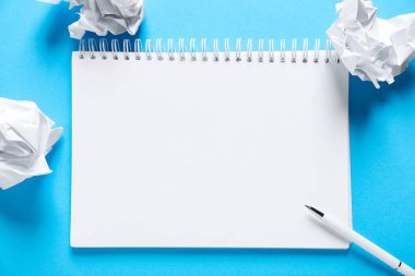 Boş bir defter aç, buruşmuş kağıt ve kalem açık mavi arkaplanda, düz uzan