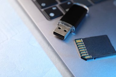 Flaş bellek, hafıza kartı ve laptop açık gri masada, yakın plan. Metin için boşluk