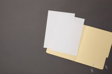 Dosya klasöründe boş kağıtlar ve gri arkaplan ataçları var. Metin için boşluk