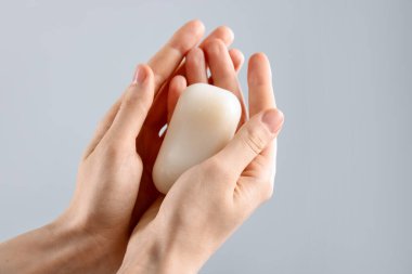 Açık gri arka planda sabun çubuğu olan kadın, yakın plan.