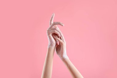 Açık pembe arka planda ellerini sabunla yıkayan kadın, yakın plan.
