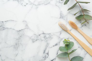 Bambu diş fırçaları ve okaliptüs dalları beyaz mermer masada, düz yerde. Metin için boşluk