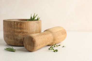 Biberiyeli ahşap havan topu, kekik ve tokmak beyaz masada, yakın plan.