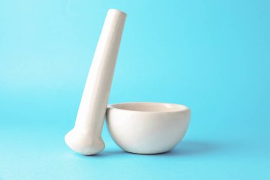 Açık mavi arkaplanda seramik havan ve tokmak, yakın plan