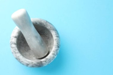 Açık mavi zemin üzerinde mermer harç ve tokmak, üst manzara. Metin için boşluk