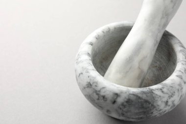 Açık gri arka planda mermer harç ve tokmak, yakın plan. Metin için boşluk