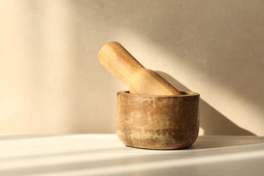 Beyaz masa içerisindeki ahşap havan ve tokmak.