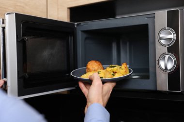 Yemek tabağını mikrodalgaya koyan adam, yakın plan.