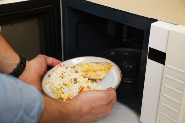 Yemek tabağını mikrodalgaya koyan adam, yakın plan.