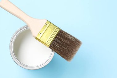 Açık mavi arka planda beyaz boya ve fırça kutusu, üst görünüm