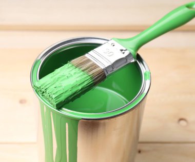 Ahşap masada yeşil boya ve fırça kutusu, yakın plan.