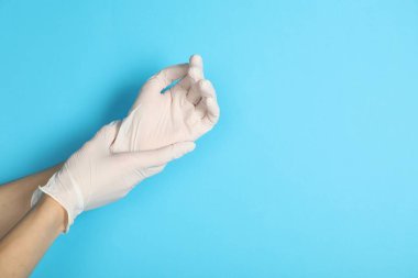 Doktor açık mavi arka plana tıbbi eldiven takıyor, yakın plan. Metin için boşluk