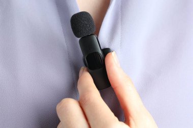 Kadın gömleğine mikrofon takıyor, yakın plan.