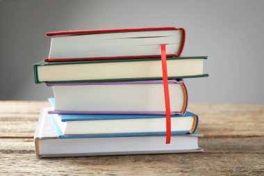 Kırmızı kurdele yer imi ve ahşap masadaki renkli kitap gri arkaplanda, yakın plan