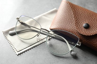 Şık gözlüklü çanta ve gri masadaki temizlik bezi, yakın plan.
