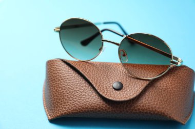 Açık mavi arka planda şık gözlüklü çanta, yakın plan