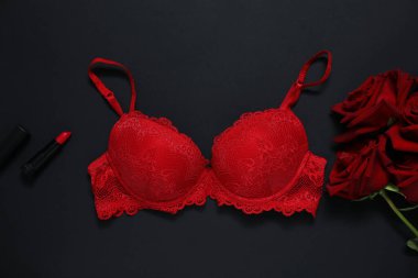 Dantelli sütyen, kırmızı güller ve siyah arka planda ruj, düz yatış.