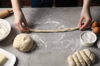 Açık gri masada simit yapan kadın, yakın plan.