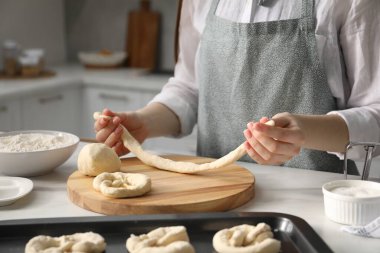 Mutfaktaki masada simit şekillendiren kadın, yakın plan.