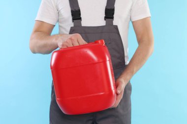 Açık mavi arka planda plastik kutu tutan adam, yakın plan.