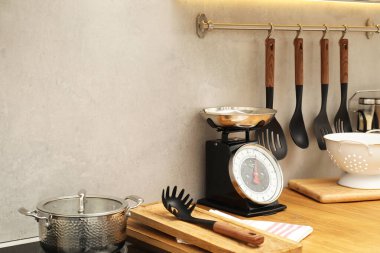 Retro mechanical kitchen scale and other utensils on wooden countertop indoors